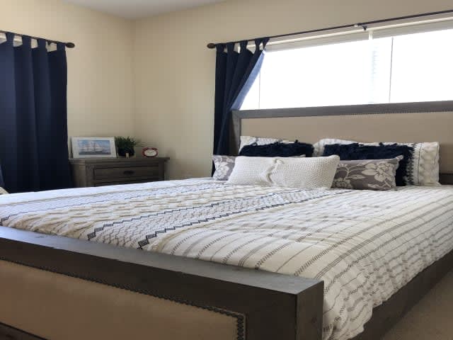 A neatly arranged bedroom with a large bed, striped bedding, and dark curtains.
