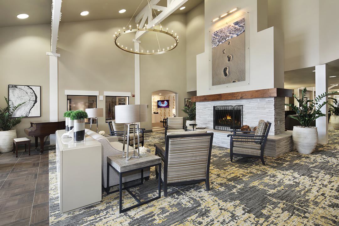 A spacious and modern living room featuring elegant seating, a central fireplace, and a striking chandelier.