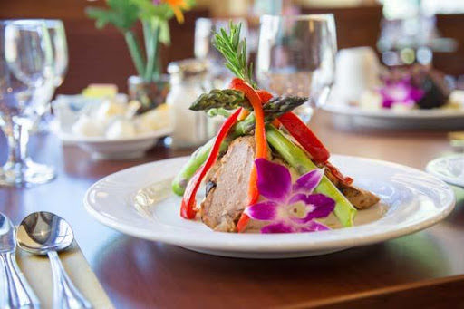 A beautifully presented gourmet dish featuring a medley of vegetables and a floral garnish.