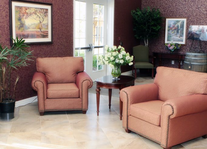 A cozy living room with two armchairs and a coffee table adorned with a floral arrangement.