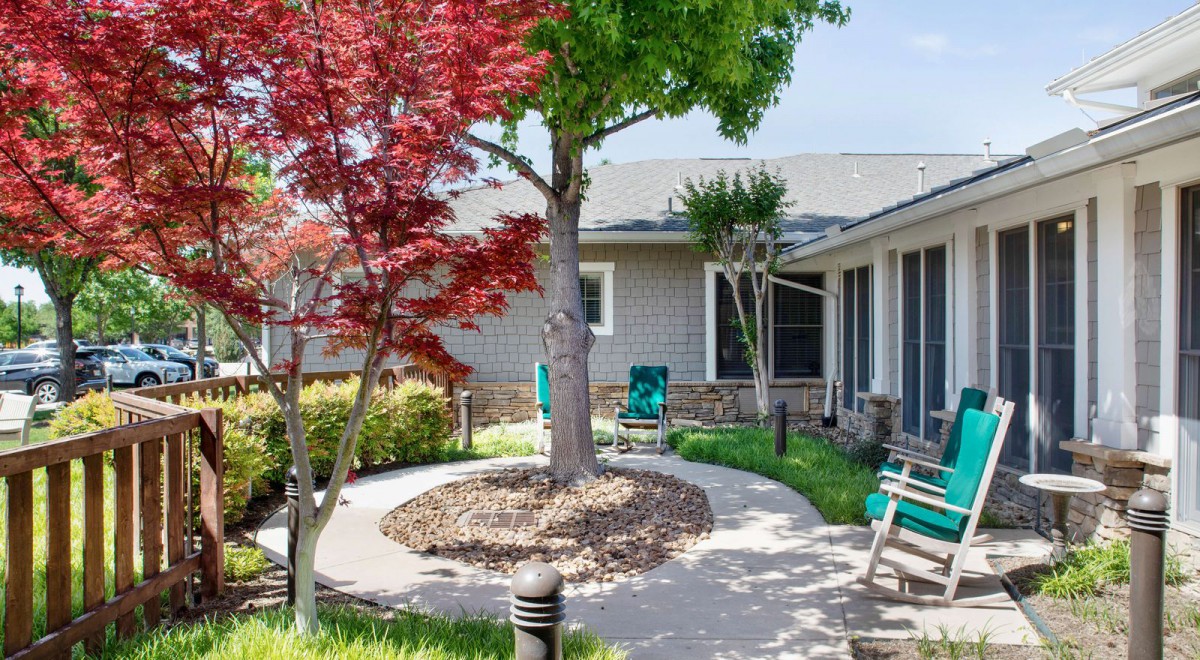 A tranquil courtyard featuring a tree surrounded by a stone path, with benches and outdoor seating for relaxation.
