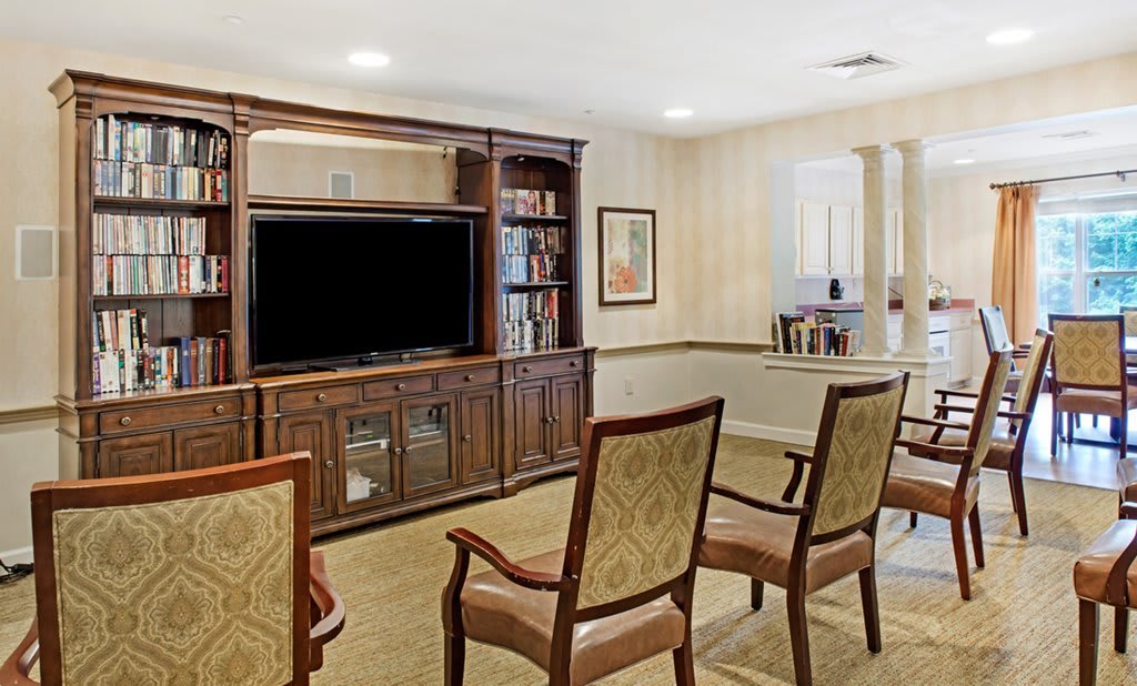 A cozy living room with wooden furniture, featuring a large television and bookshelves.