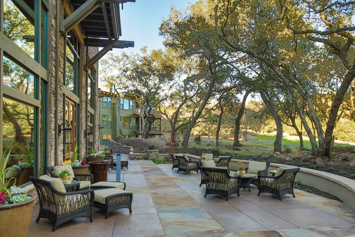 A spacious outdoor patio area surrounded by trees, featuring comfortable seating and a natural landscape.