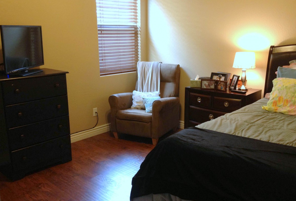 Cozy bedroom with a chair, dresser, and soft lighting.