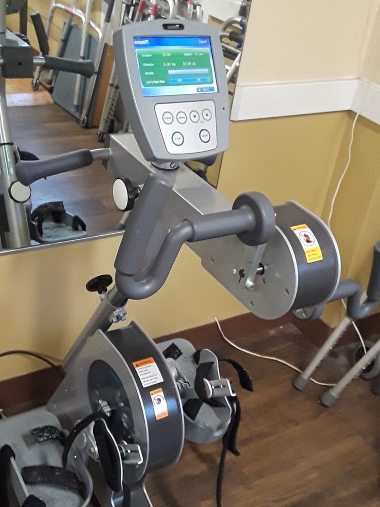 A gym cardio machine, designed for upper body workouts, displayed in a fitness center.