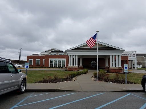 A view of a well-structured building featuring an American flag in front, set against a cloudy sky.