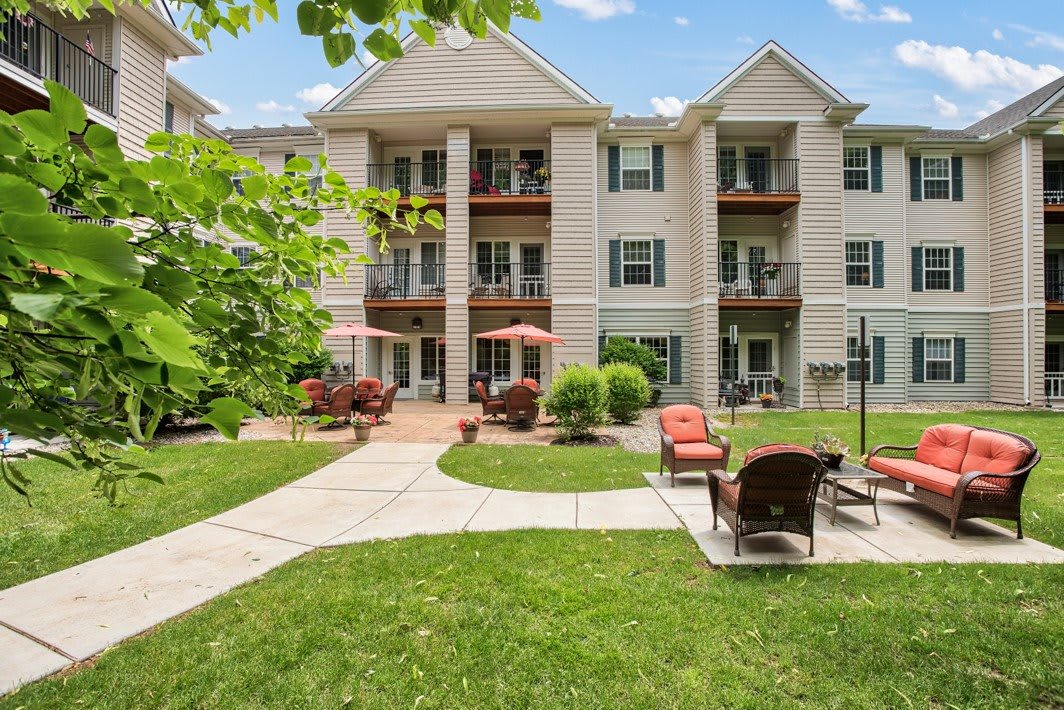 Three-story apartment building with a landscaped courtyard and outdoor seating.