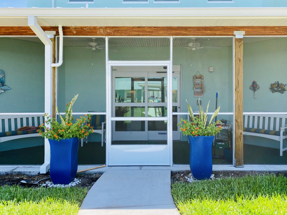 A modern entrance with glass doors flanked by large blue planters.