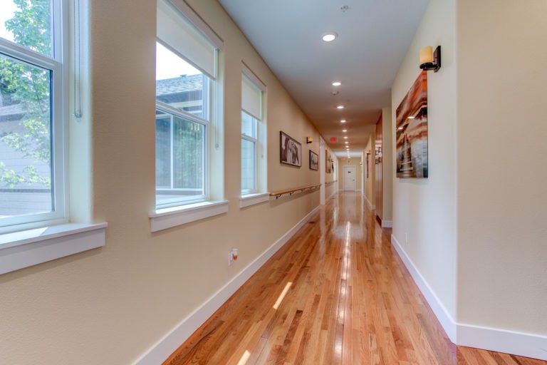A long, well-lit hallway with wooden floors and artwork on the walls.