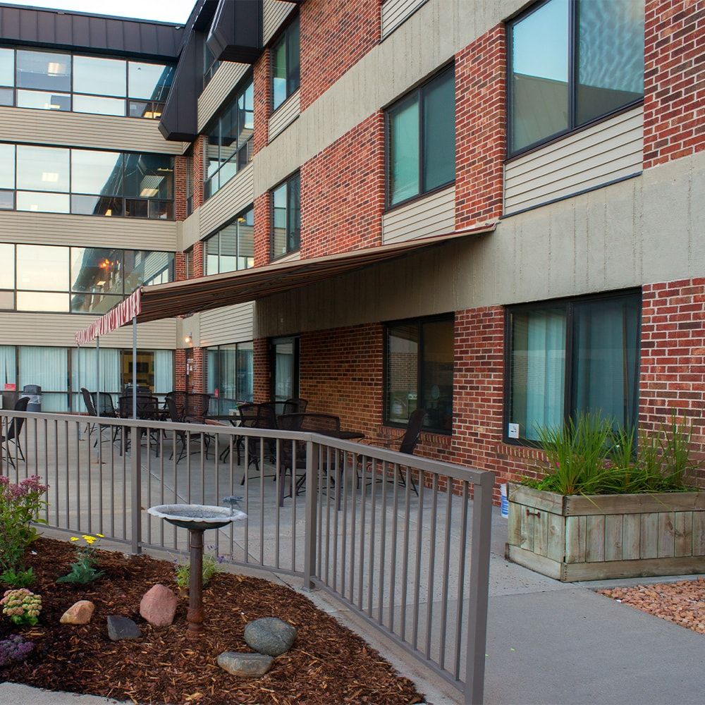 A modern brick building with large windows and a landscaped outdoor area featuring railings and garden elements.