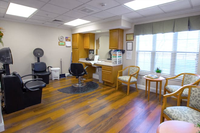 A hair salon interior with styling chairs, a mirror, and a small waiting area.