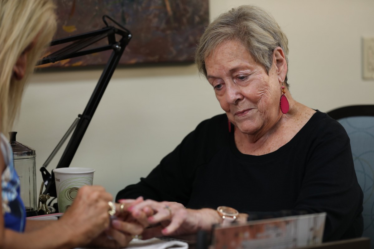 An elderly woman is focused on reading something indoors.