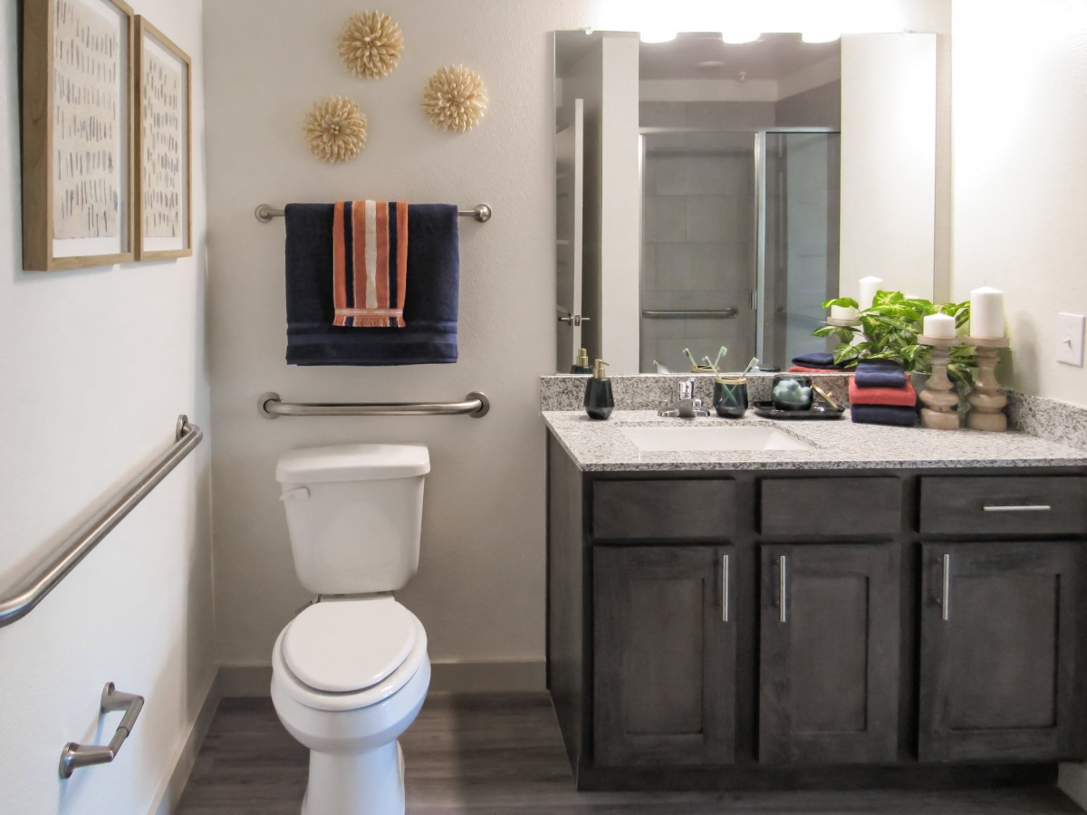 A neatly organized bathroom featuring a toilet, sink, and mirror with decorative elements.