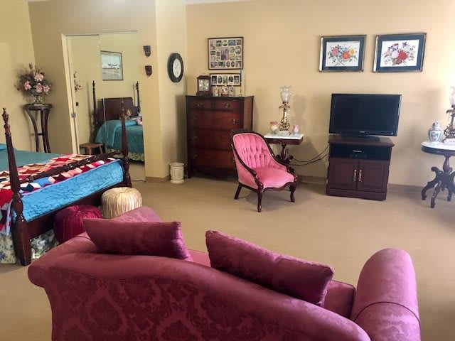 A cozy living room with pink furniture and a TV setup.