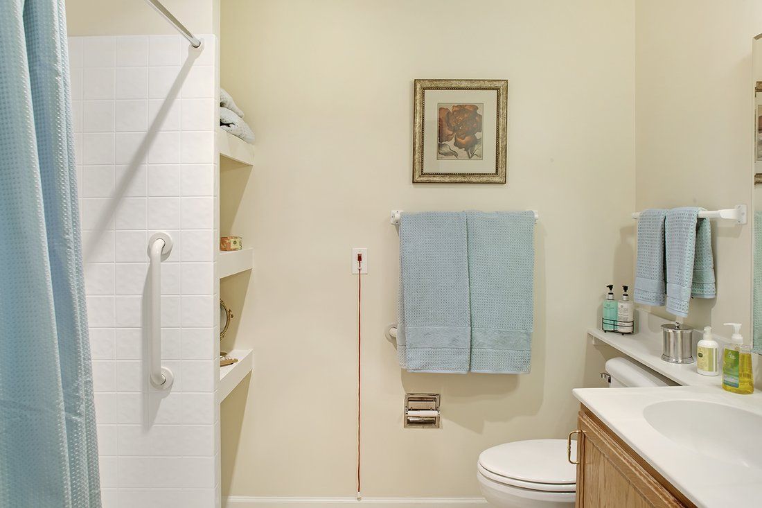 A neatly organized bathroom with a towel rack, shelving, and simple decor.