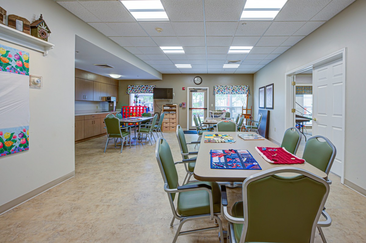 A brightly lit community room with tables and chairs, featuring board games set up for use.