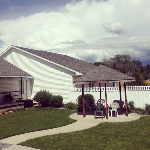 A serene backyard setting featuring a play area, well-kept lawn, and distant clouds.