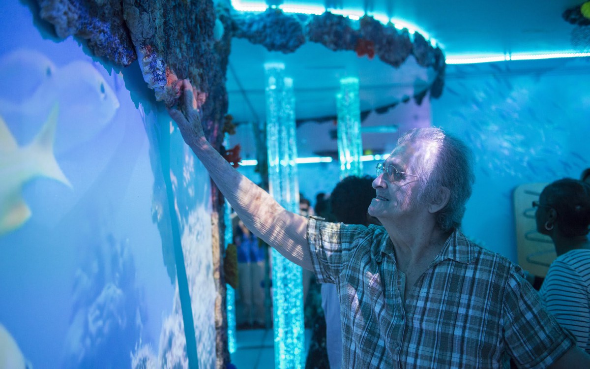 A man interacts with a vibrant, blue-lit art installation.