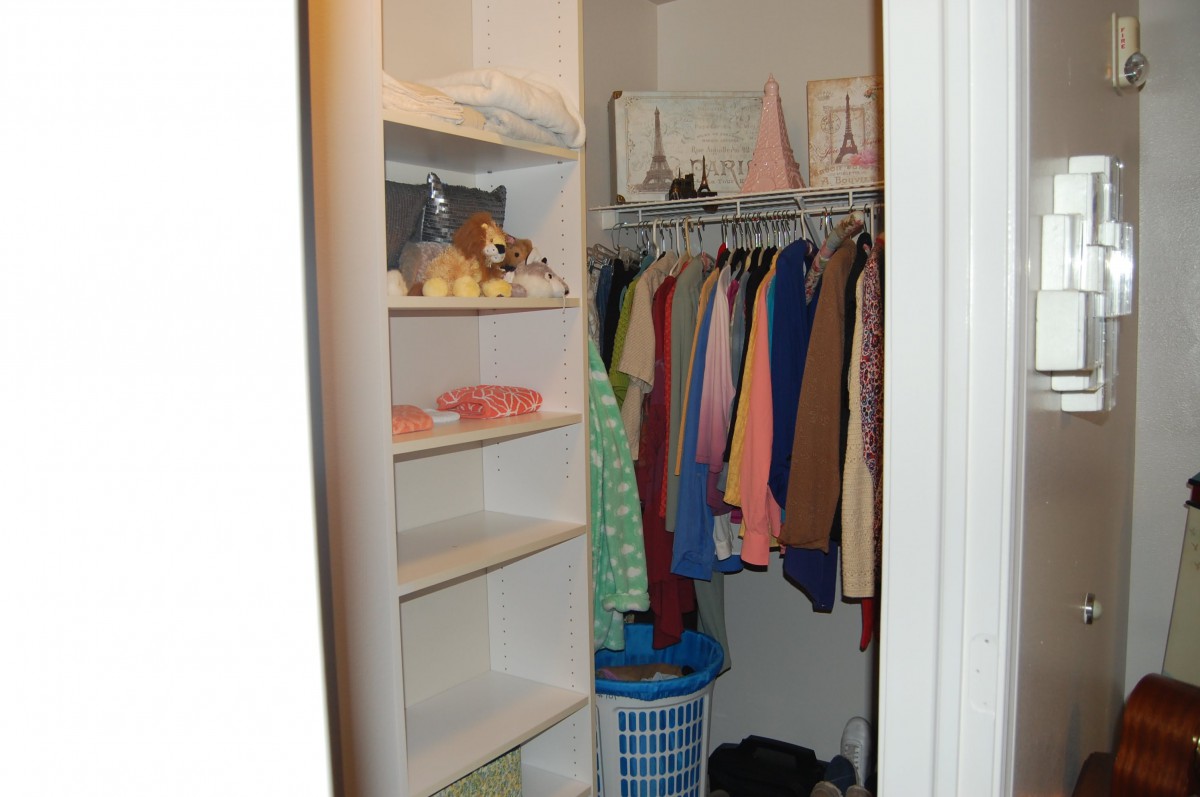 A neatly organized closet with hanging clothes and shelves.