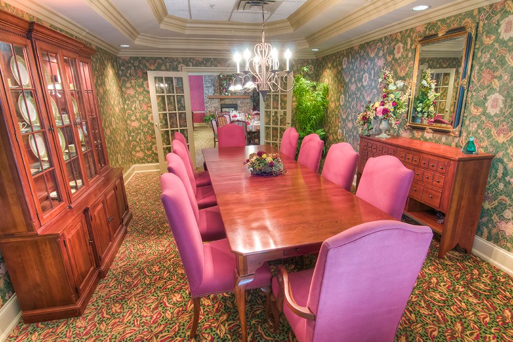 Elegant dining room with pink chairs and a wooden table.
