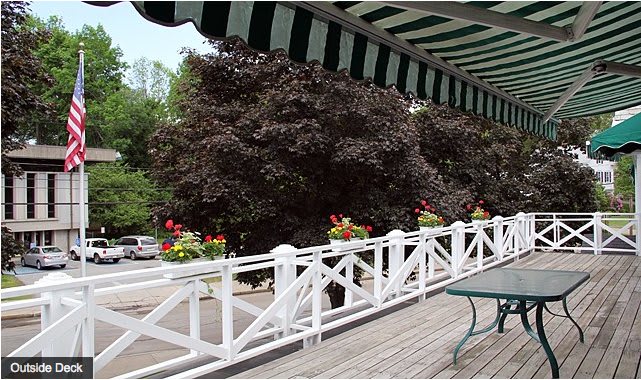 A scenic outdoor patio with a striped awning and white fence adorned with colorful flowers.