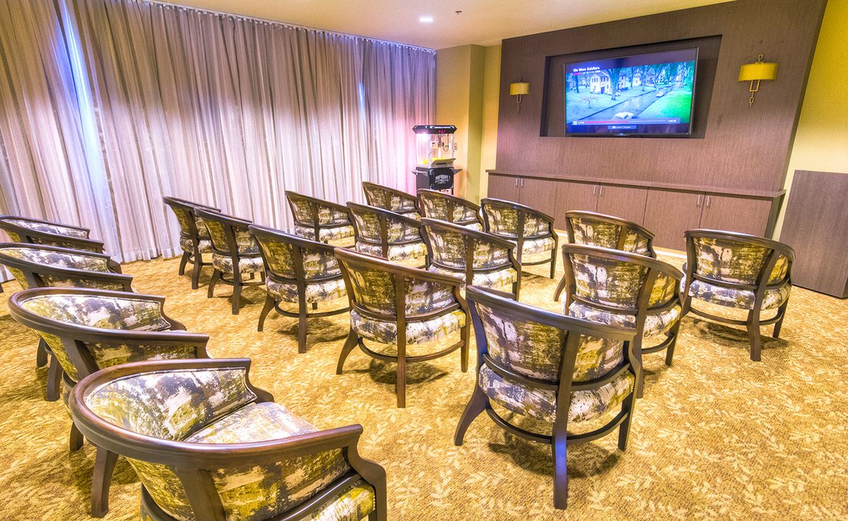 A cozy home theater setup with rows of chairs facing a large screen.