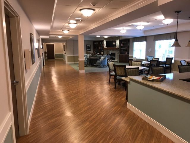 A spacious and well-lit hallway with seating areas and a wooden floor, featuring modern decor.