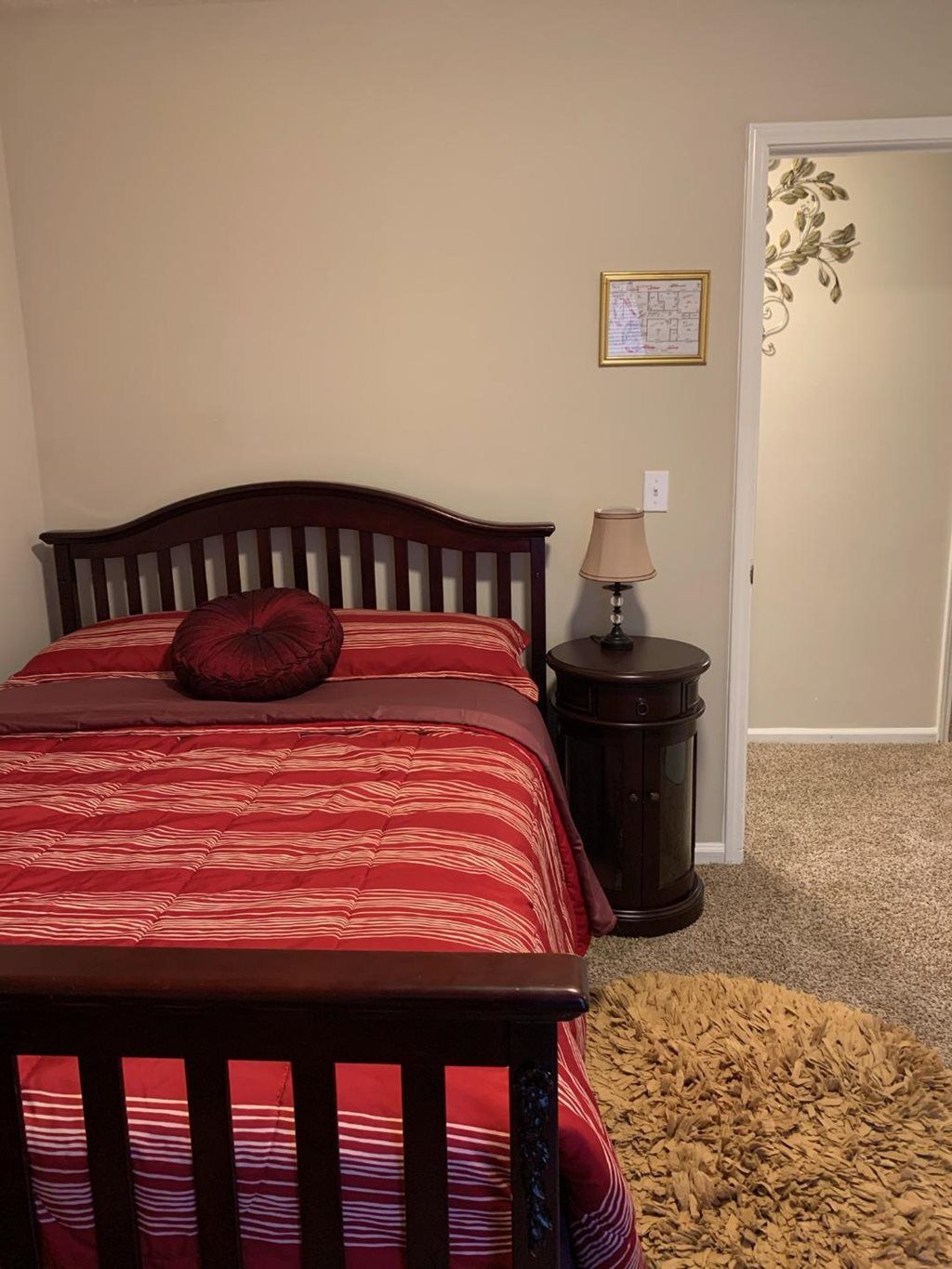 Cozy bedroom with red bedding and a wooden nightstand.