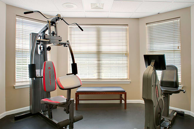 A well-equipped gym with exercise machines and a bench in a bright workout room.