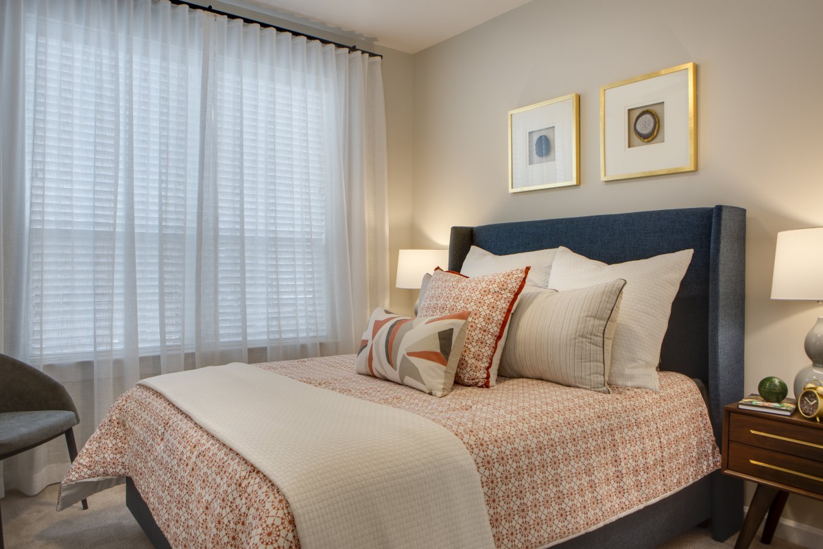 A cozy bedroom with neatly arranged pillows, soft lighting, and elegant decor.