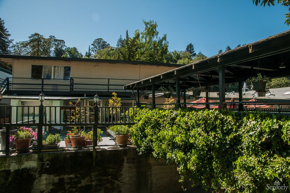 A building with a balcony surrounded by greenery and trees.