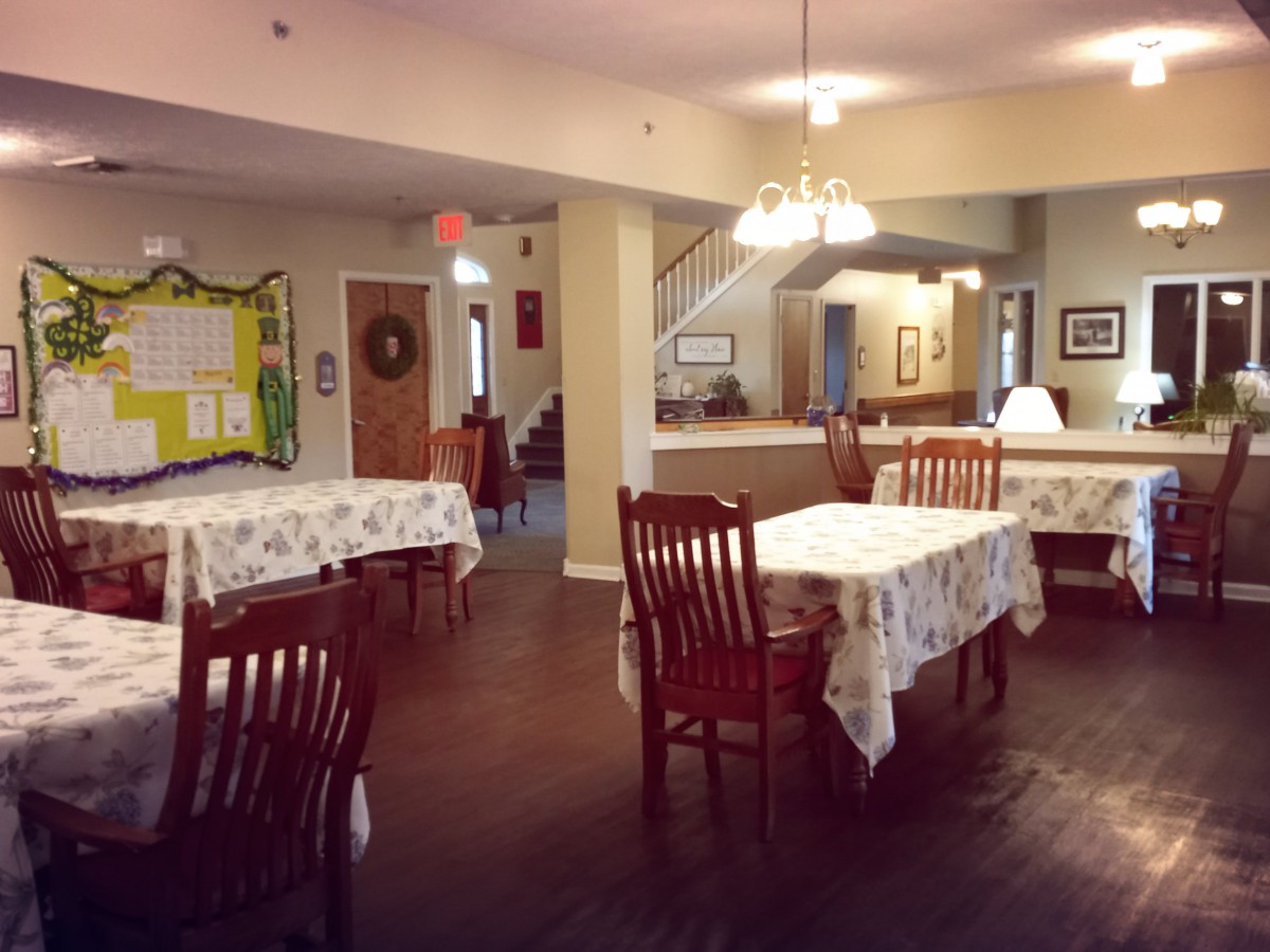 A cozy dining area with neatly arranged tables and chairs, decorated with warm lighting.