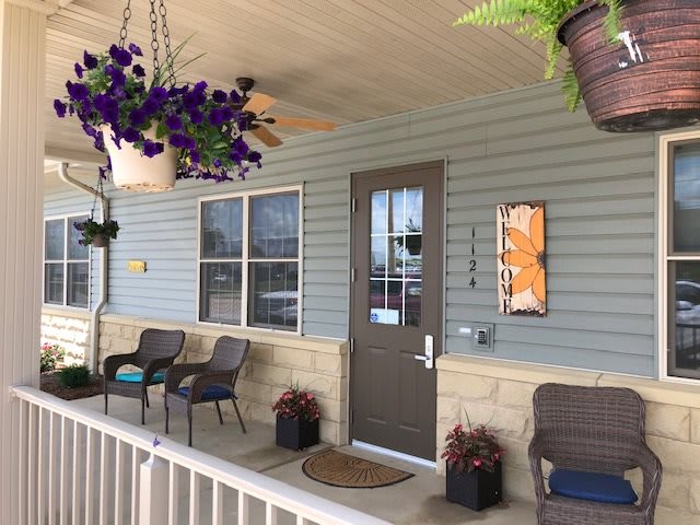 A cozy porch with seating and vibrant hanging plants.