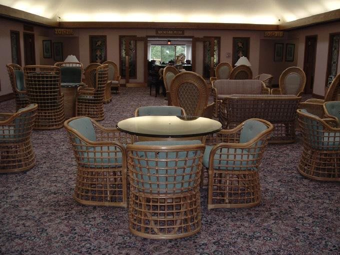 A cozy indoor lounge area featuring rattan chairs and a glass-top table.