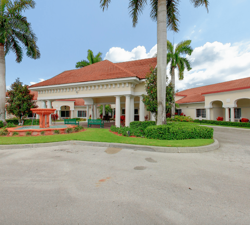 A beautiful entrance to a tropical-style building with red roofs and lush landscaping.