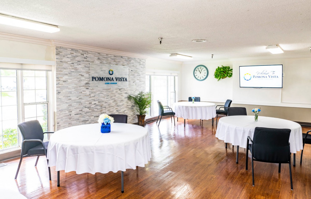 A well-lit conference room with round tables covered in white tablecloths and minimalist decor.