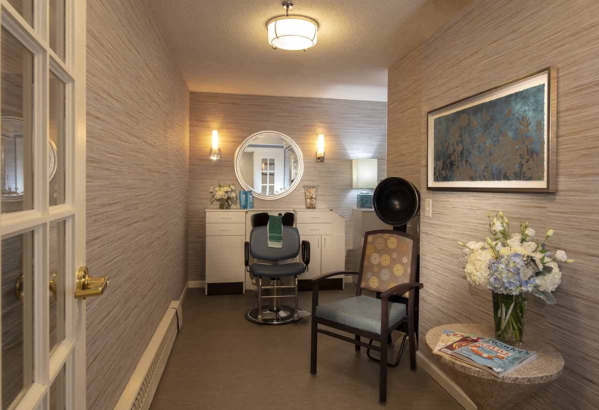 A cozy hair salon interior featuring a styling chair, mirror, and hair dryer.