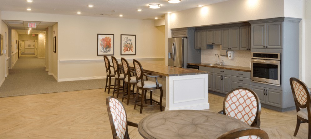 A modern kitchen interior featuring a large countertop with bar stools and a round table.