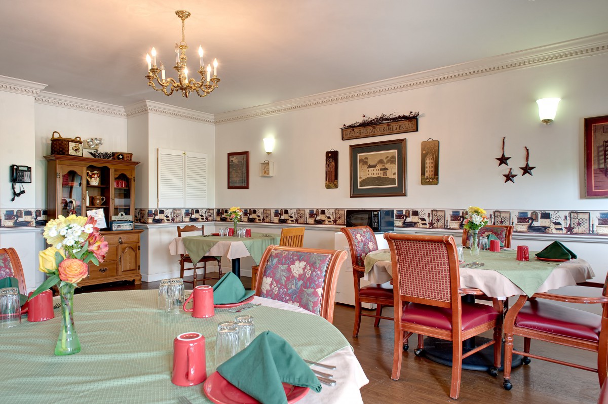 A cozy dining room with elegantly set tables and a chandelier.