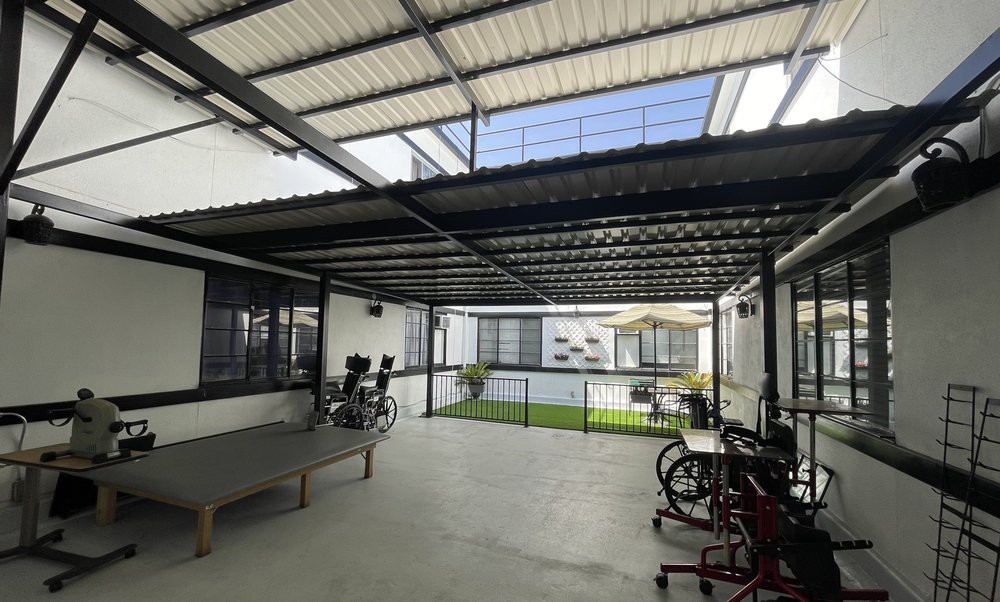 A spacious patio with a metal roof, featuring bicycles and a ping pong table.