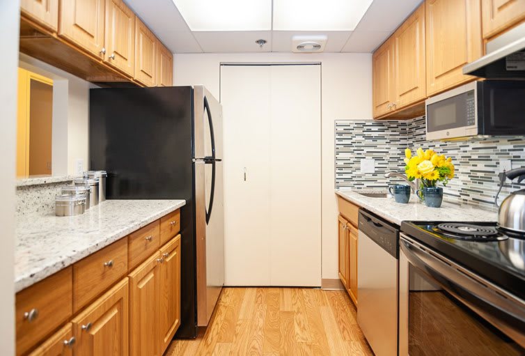 A modern kitchen with wooden cabinets, stainless steel appliances, and a decorative backsplash.