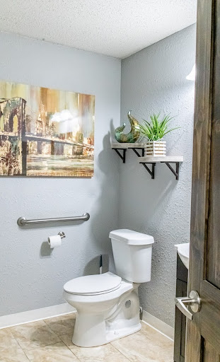A stylish and modern bathroom featuring decorative shelves, wall art, and a touch of greenery.
