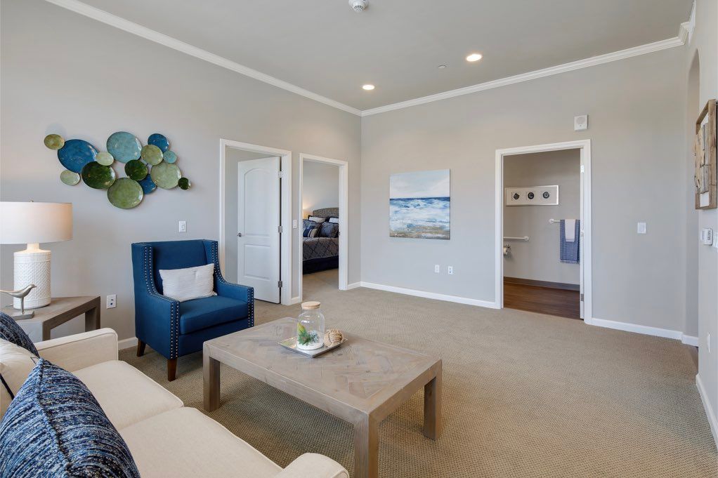 A modern living room featuring a blue armchair, neutral tones, and wall artwork.