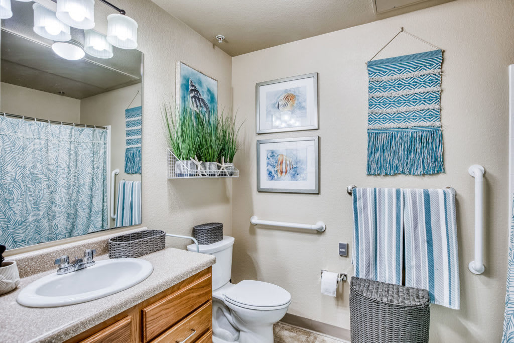 A well-decorated bathroom featuring wall art, plants, and neatly arranged towels.