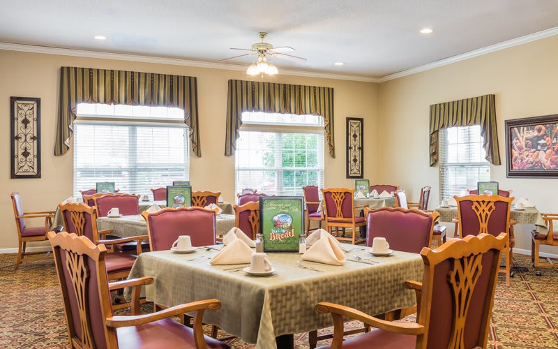 A well-arranged dining area with set tables and comfortable chairs in a light-filled room.