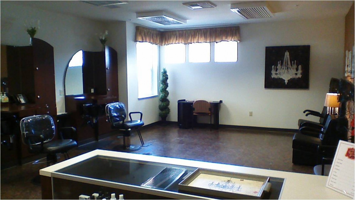 An empty hair salon with chairs and mirrors, featuring a large window and minimal decor.