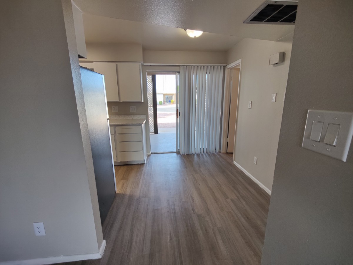 A modern apartment kitchen with wood flooring and sliding glass doors.