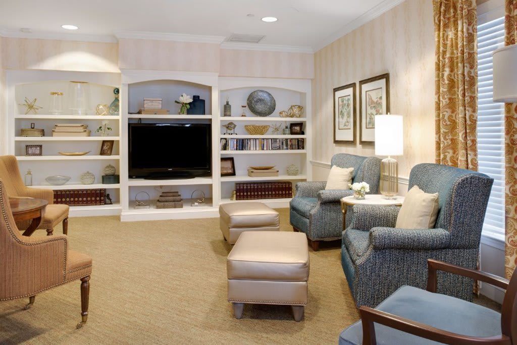 A cozy living room with built-in bookshelves, a large television, and comfortable armchairs.