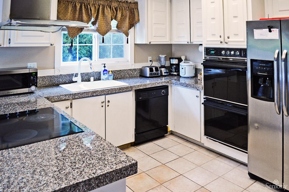 A modern kitchen featuring white cabinets, granite countertops, and a double oven.