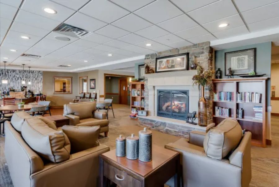A cozy living room with a fireplace, comfortable seating, and bookshelves.